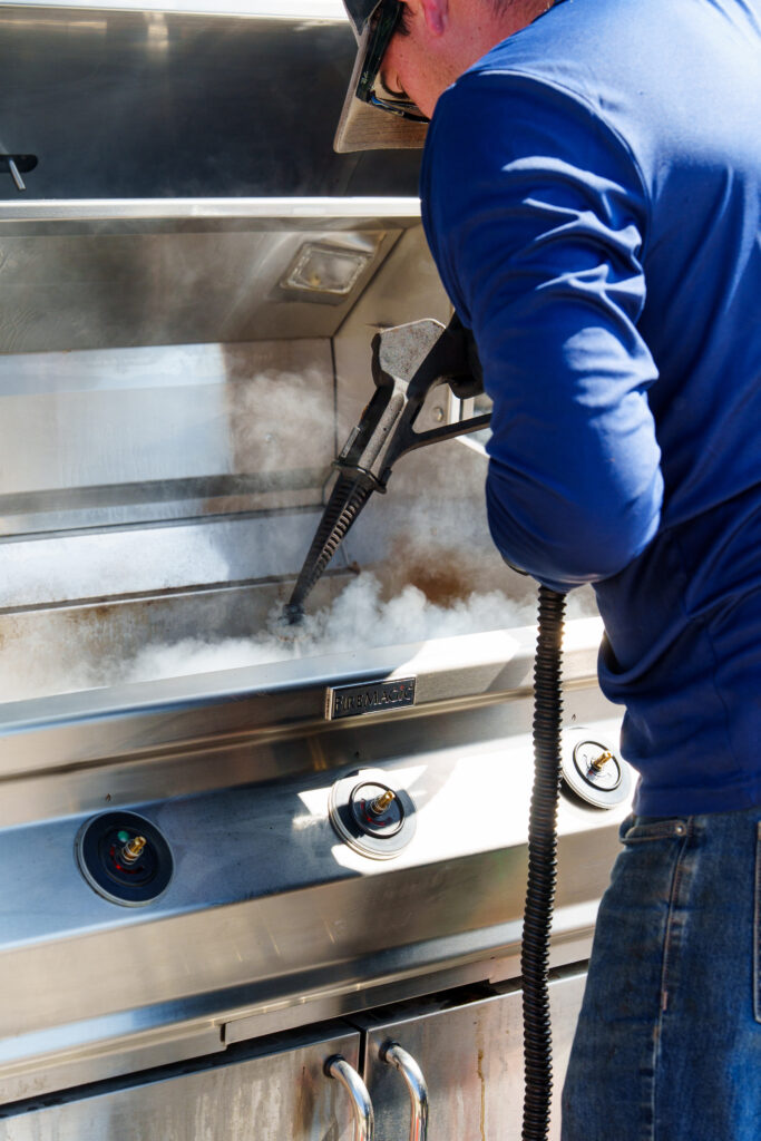 Fire Metal employee steam cleaning a grill